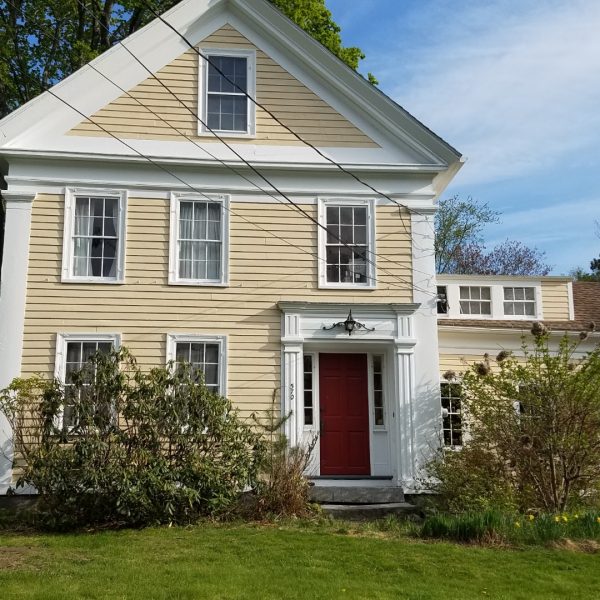 after photo of home with yellow exterior and red door