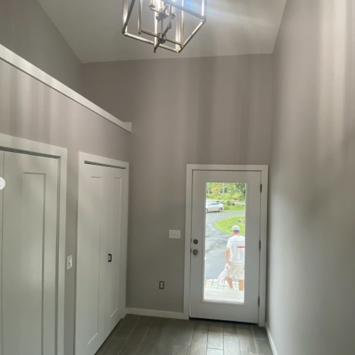 Mudroom painted light grey with white eggshell color doors and trim.